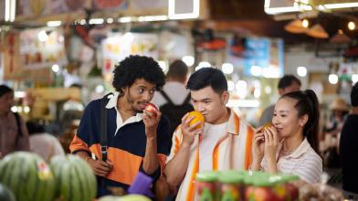 A group of friends at a market inspecting produce and enjoying the smells as a means of mindful eating for healthier life choices around diabetes management
