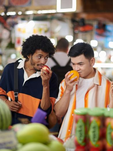 A group of friends at a market inspecting produce and enjoying the smells as a means of mindful eating for healthier life choices around diabetes management