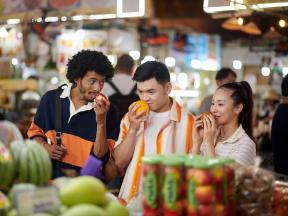 A group of friends at a market inspecting produce and enjoying the smells as a means of mindful eating for healthier life choices around diabetes management