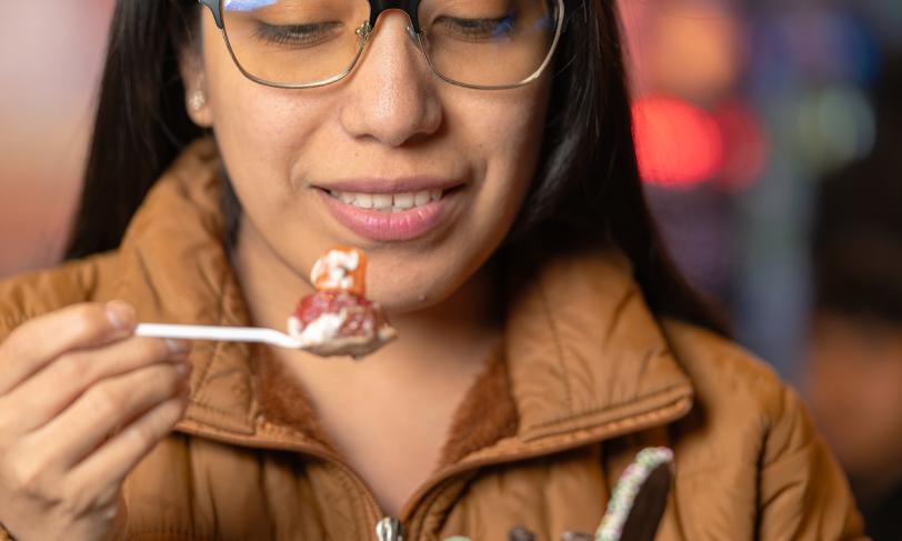 A woman eating a spoon of strawberry and cream for a fruit forward dessert