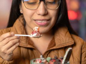 A woman eating a spoon of strawberry and cream for a fruit forward dessert