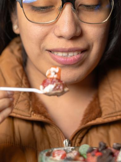 A woman eating a spoon of strawberry and cream for a fruit forward dessert
