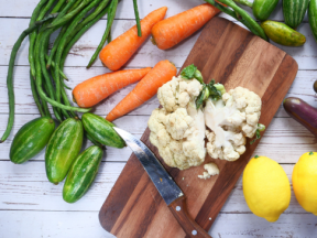 A chopping board with cauliflower surrounded by veggies perfect for a healthy diabetic diet