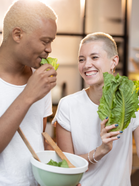 A couple joking together while making a salad for a healthy diet