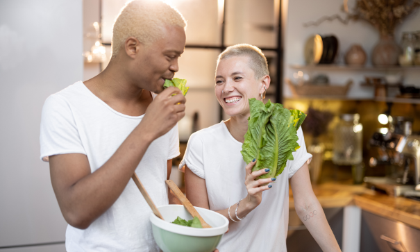 A couple joking together while making a salad for a healthy diet